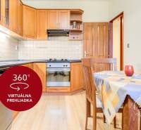 Konyha egy kétszobás lakásban fa dekoros munkalappal, étkezőasztallal és padlóval.