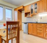 Konyha fa szekrényekkel, étkezőasztallal és fa dekorációjú padlóval egy kétszobás lakásban.