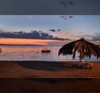 A fotó egy tengerparti estét ábrázol pálmafákkal és a Reality BICIAŇ ingatlanközvetítő irodával.