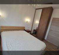 Rekreációs apartman kényelmes ággyal és fa dekorációjú padlóval, falilámpákkal megvilágítva.