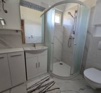 Fürdőszoba a nyaraló apartmanban modern zuhanyzóval és fehér bútorokkal.