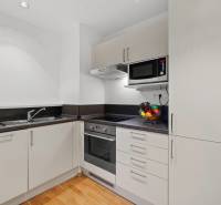 Konyha egy kétszobás lakásban fehér szekrényekkel és fa dekor padlóval.