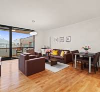 Nappali egy kétszobás lakásban ülőgarnitúrával, étkezőasztallal és fa mintázatú padlóval.