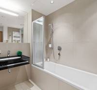 Fürdőszoba káddal, fekete mosdóval és tükörrel egy kétszobás lakásban.