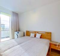 Hálószoba egy háromszobás lakásban ággyal és kilátással az erkélyajtón keresztül.