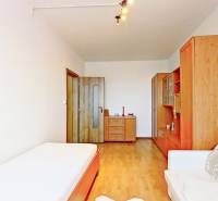 Szoba egy háromszobás lakásban, fa dekorációjú padlóval és egyszerű bútorokkal.