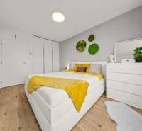 Világos hálószoba ággyal, fehér bútorokkal, növényekkel és fa mintázatú padlóval egy 4 szobás lakásban.