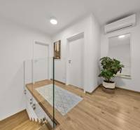 Folyosó egy 4 szobás lakásban fa mintás padlóval, tükörrel és növénnyel.