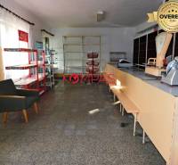 Kereskedelmi helyiségek belső tere pulttal, polcokkal és székkel.