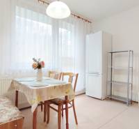 Konyha egy kétszobás lakásban étkezőasztallal, székekkel és hűtőszekrénnyel.