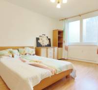 Hálószoba egy kétszobás lakásban ággyal, bútorokkal és fa dekorációjú padlóval.