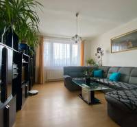 Nappali nagy szürke kanapéval, üvegasztallal és fa dekoros padlóval.