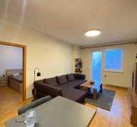 Nappali egy kétszobás lakásban kanapéval és fa mintázatú padlóval.