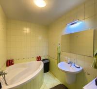 Fürdőszoba egy kétszobás lakásban káddal, mosdóval és tükörrel a falon.