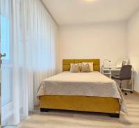 Hálószoba egy egyszobás lakásban ággyal, íróasztallal és fa dekorációjú padlóval.