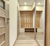 1 szobás lakás belső tere fa hatású padlóval, szekrényekkel és fogasfallal.