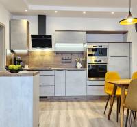 Konyha egy egyszobás lakásban fa dekor padlóval, étkezőasztal és sárga székek.