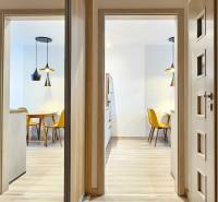 Világos étkező konyhaasztallal és sárga székekkel egy garzonlakásban.