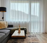 Stílusos nappali egy egyszobás lakásban kanapéval és asztallal fa dekorációjú padlón.