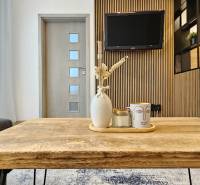 A nappali rész egy egyszobás lakásban faasztallal és dekorációkkal a háttérben egy televízióval.