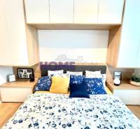 Hálószoba egy háromszobás lakásban fa dekor padlóval és virágmintás ágyneművel.