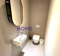 Fürdőszoba egy háromszobás lakásban tükörrel, mosdóval és függesztett WC-vel.