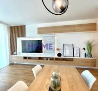 Világos nappali egy háromszobás lakásban, fa dekoros padlóval és modern vonalvilágítással.