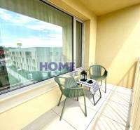 Erkély kilátással, ülőhelyekkel és dekoratív asztallal egy háromszobás lakásban.