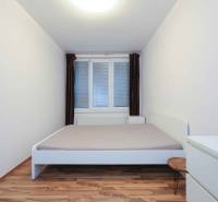 Hálószoba egy kétszobás lakásban fehér bútorokkal és fa dekorációjú padlóval.