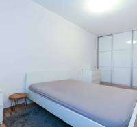 Hálószoba egy kétszobás lakásban nagy beépített szekrénnyel és fa dekorációjú padlóval.