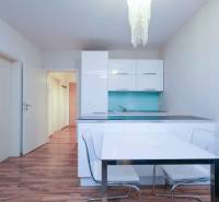 Egy kétszobás lakás konyhája fehér szekrényekkel, kék hátlappal és fa dekorációjú padlóval.