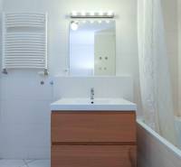 Fürdőszoba egy kétszobás lakásban mosdóval, tükörrel és káddal.