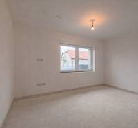 Tágas szoba egy családi házban, ablakkal, amely egy másik házra néz.