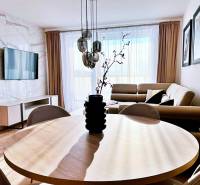 Nappali egy háromszobás lakásban, fa dekorációjú padlóval és kényelmes kanapéval.