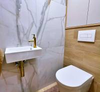 Fürdőszoba kerámia mosdóval, tükörrel és fa dekorációjú padlóval egy háromszobás lakásban.