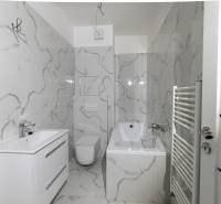 Fürdőszoba márvány dekorációjú falakkal, káddal és mosdóval egy kétszobás lakásban.