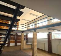 Beltéri üzlethelyiségek fa mintázatú padlóval és fém lépcsővel.