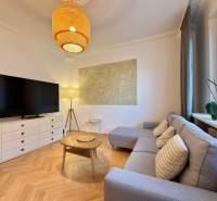 Nappali egy kétszobás lakásban fa mintázatú padlóval, kanapéval és TV-vel.