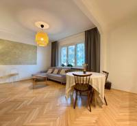 Nappali egy kétszobás lakásban barna kanapéval és fa dekoros padlóval.