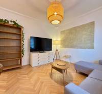 Nappali egy kétszobás lakásban, fa dekor padlóval és kényelmes kanapéval.