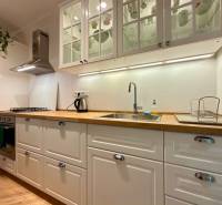 Világos konyha egy kétszobás lakásban, fa mintázatú padlóval és fehér szekrényekkel.