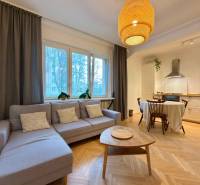 Nappali konyhával és étkezőasztallal, fa dekorációjú padló, világos kanapé.