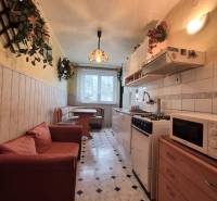 Konyha egy háromszobás lakásban étkező sarokkal, kanapéval és mintás padlóval.