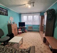 Nappali egy háromszobás lakásban türkiz falakkal, bútorokkal és szőnyegpadlóval.