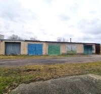 Épület színes garázskapukkal Kuklovban, aszfaltút mellett.