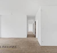 Fehér folyosó egy családi házban, fa dekorációjú padlóval és üvegezett ajtókkal az udvarra.