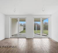 Egy családi házban van egy tágas szoba nagy ablakokkal és fa dekorációjú padlóval.