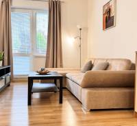 Nappali egy kétszobás lakásban kanapéval, fa dekor padlóval és televízióval.