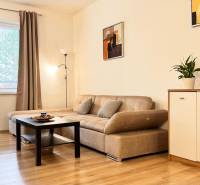 Nappali egy kétszobás lakásban bézs kanapéval, fa mintázatú padlóval.