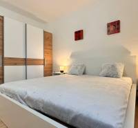 Hálószoba egy kétszobás lakásban nagy ággyal, gardróbszekrénnyel és fa dekoros padlóval.